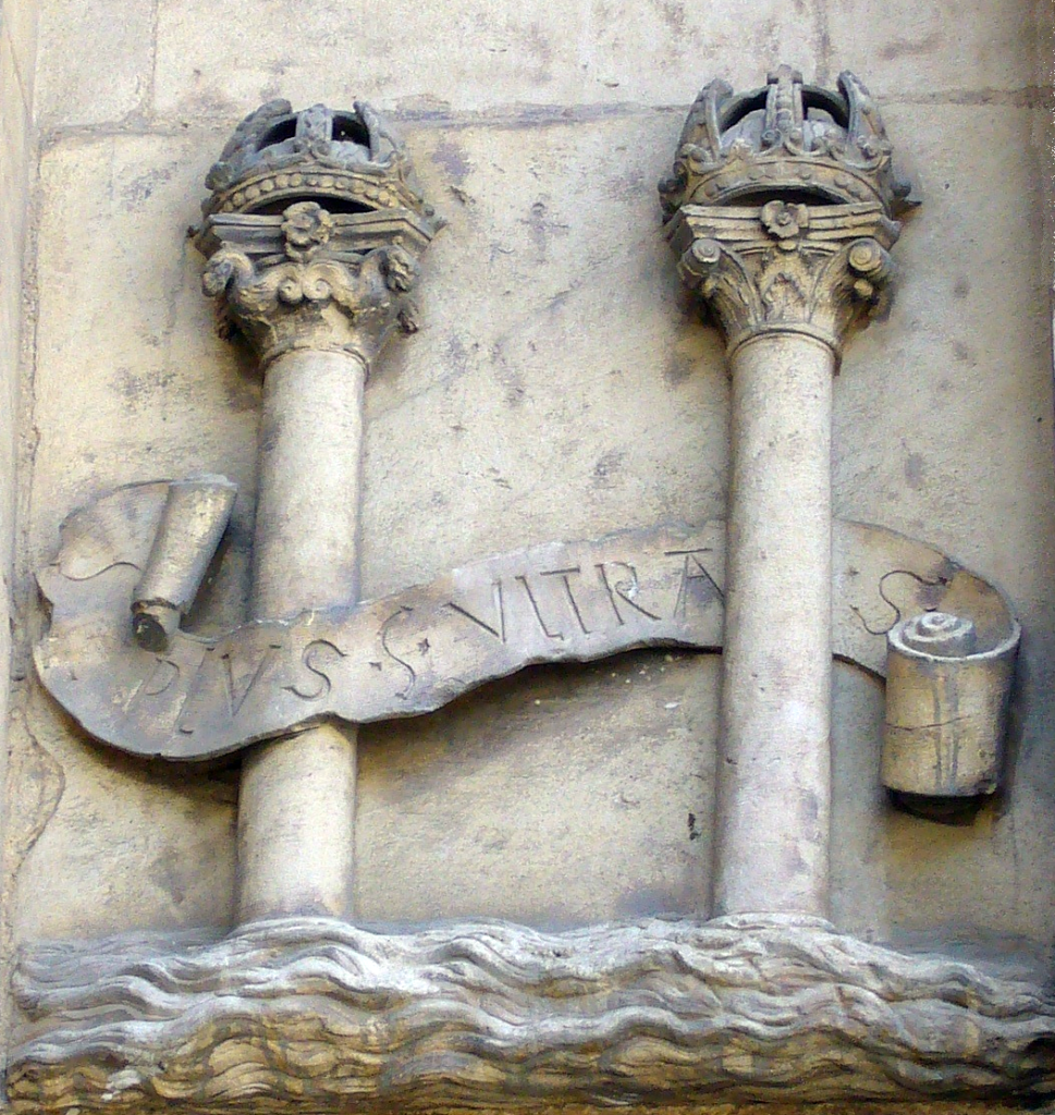 Sculpture inspired by the coat of arms of Spain.  Photo by Ignacio Gavira at the city hall in Seville, Spain.  The inscribed motto, although in the negative form (Non Plus Ultra), was said to have been on the ancient Pillars of Hercules warning ships to travel no further.  After landing in the New World in 1492, Spain would refashion this phrase to the affirmative and seize it as their national motto.  Less than a century later, Spain would become known as the first "empire on which the sun never sets".  A leading theory is that this coat of arms was actually the precursor to the version of the American dollar sign that uses two vertical bars.  The motto and the pillars can be found on the modern Spanish flag.